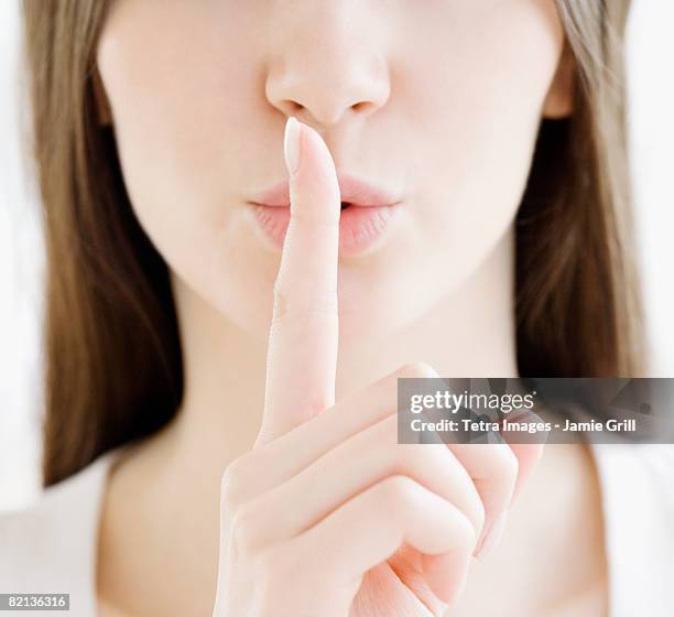 close up of woman shushing - woman with finger on lips stock pictures, royalty-free photos & images