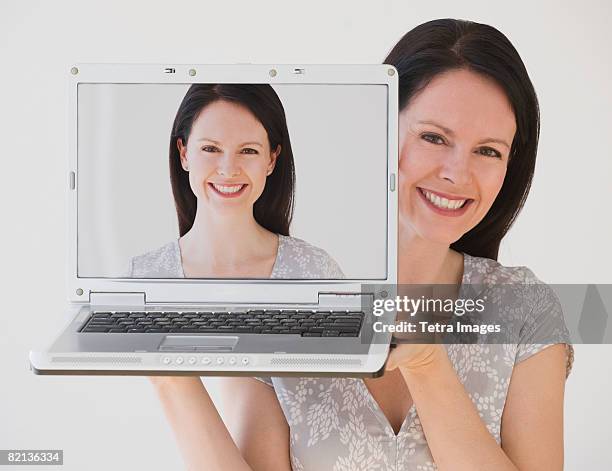 woman holding laptop next to face - photographie numérique photos et images de collection