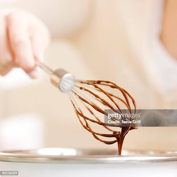 woman holding whisk with chocolate batter - whipping woman stock pictures, royalty-free photos & images