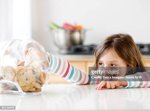 girl reaching into cookie jar - temptation stock-fotos und bilder