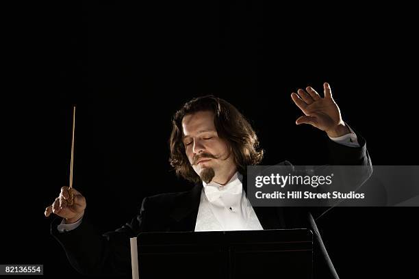 man conducting behind music stand - musical conductor stock pictures, royalty-free photos & images