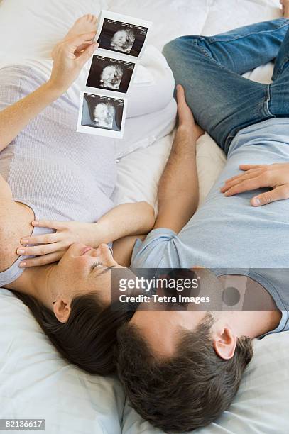 pregnant hispanic couple looking at ultrasound printout - interracial wife photos stock-fotos und bilder