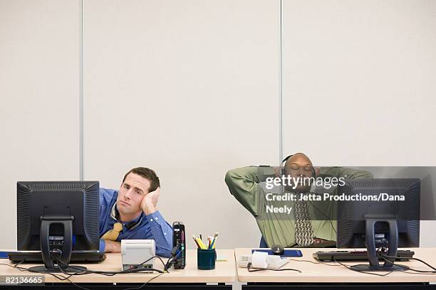 multi-ethnic businessmen sitting at desks - bored at work stock pictures, royalty-free photos & images