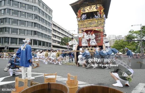 People take part in "tsuji mawashi," or turning a decorated Yamahoko float around a corner, during the Yamahoko parade of the traditional Gion...