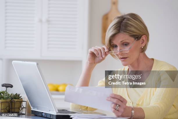 woman reading mail next to laptop - reading glasses on table stock pictures, royalty-free photos & images