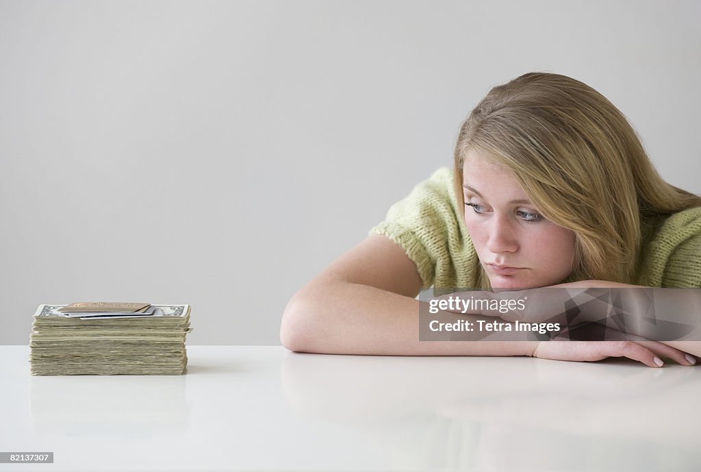 Teenaged girl looking at stack of money