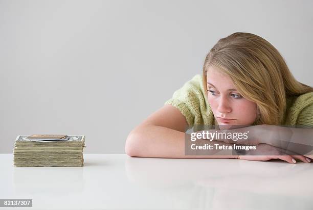 teenaged girl looking at stack of money - girl of desire stock pictures, royalty-free photos & images