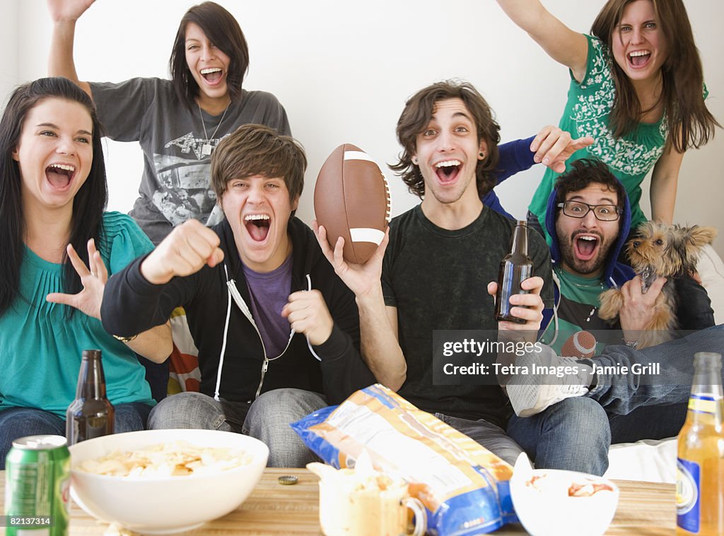 Group of friends cheering on sofa