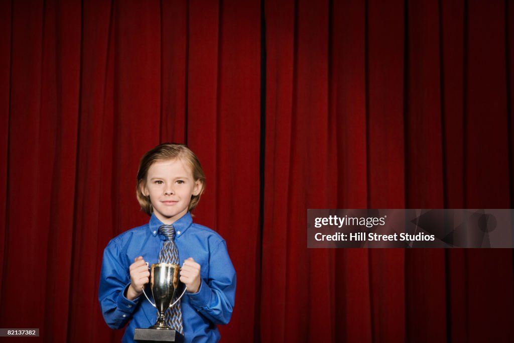 Boy holding trophy on stage