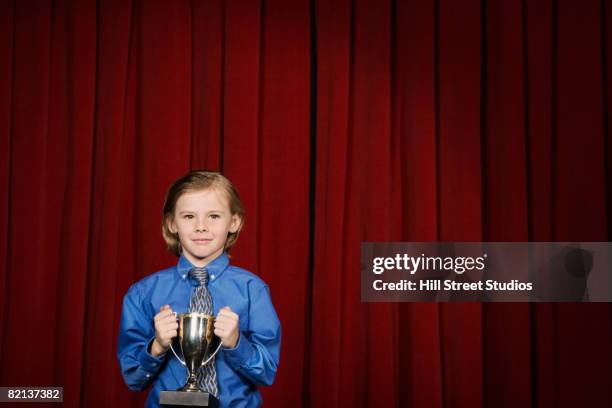 boy holding trophy on stage - spelling bee stock pictures, royalty-free photos & images