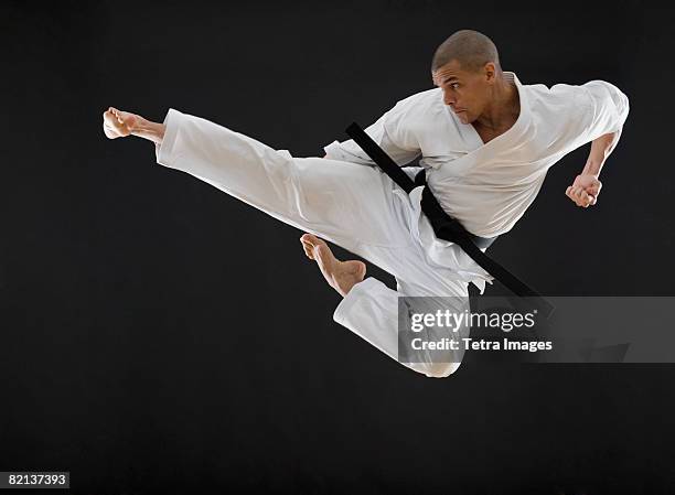 hispanic male karate black belt kicking in air - karateka stock pictures, royalty-free photos & images