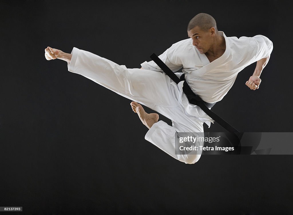 Hispanic male karate black belt kicking in air