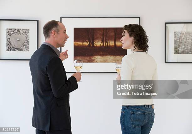 couple discussing art at art gallery - art gallery party stock pictures, royalty-free photos & images