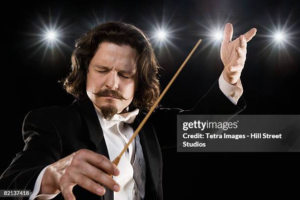 man conducting under lights - music conductor stock pictures, royalty-free photos & images