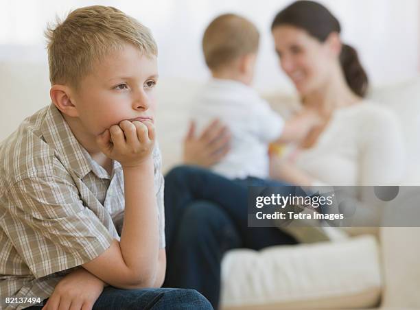 boy thinking in front of mother and baby - sibling jealousy stock pictures, royalty-free photos & images