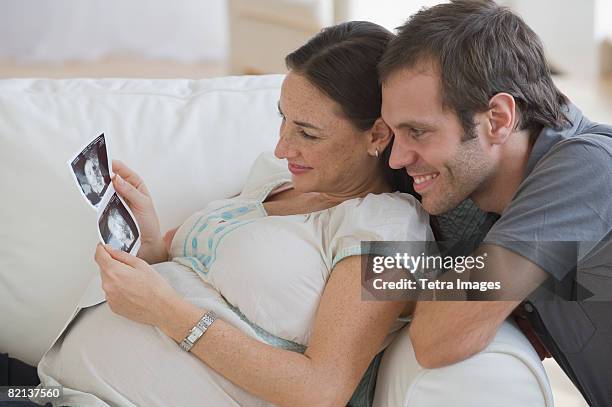 pregnant hispanic couple looking at ultrasound printout - interracial wife photos stock-fotos und bilder