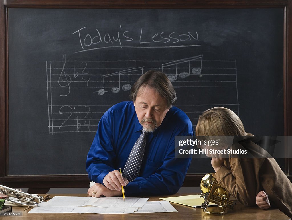 Music teacher and student in front of blackboard