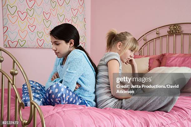 girl sitting back to back on bed - friends argue fotografías e imágenes de stock