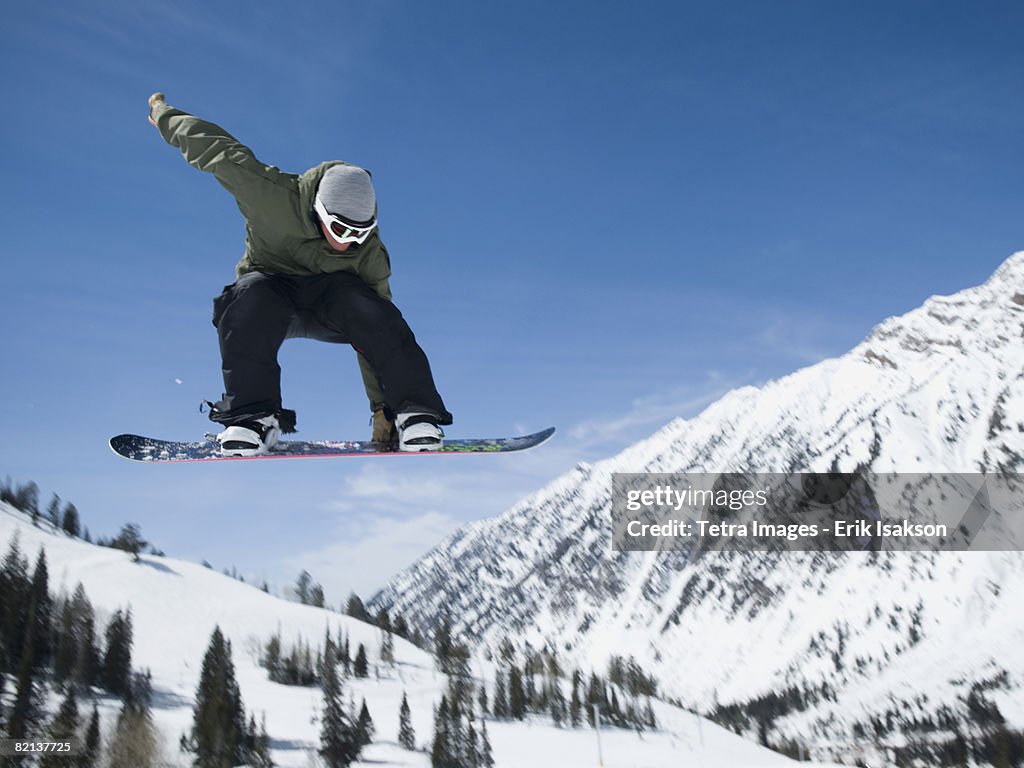 Man on snowboard in air, Wasatch Mountains, Utah, United States