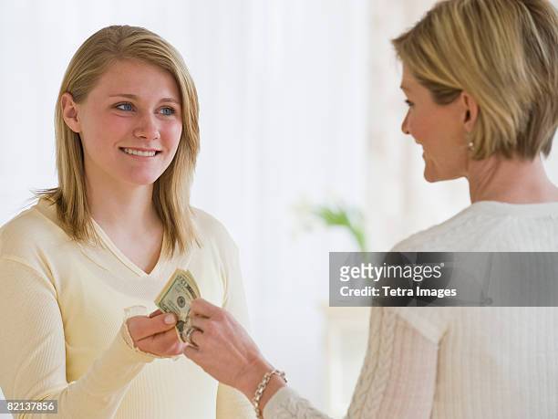 mother giving money to teenaged daughter - money borrow stockfoto's en -beelden