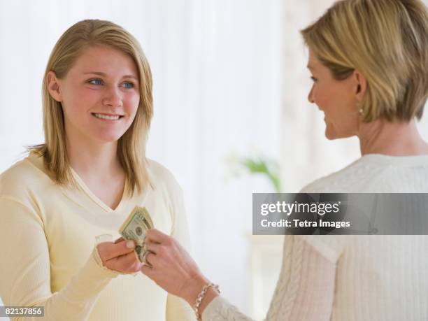 mother giving money to teenaged daughter - money borrow stock pictures, royalty-free photos & images