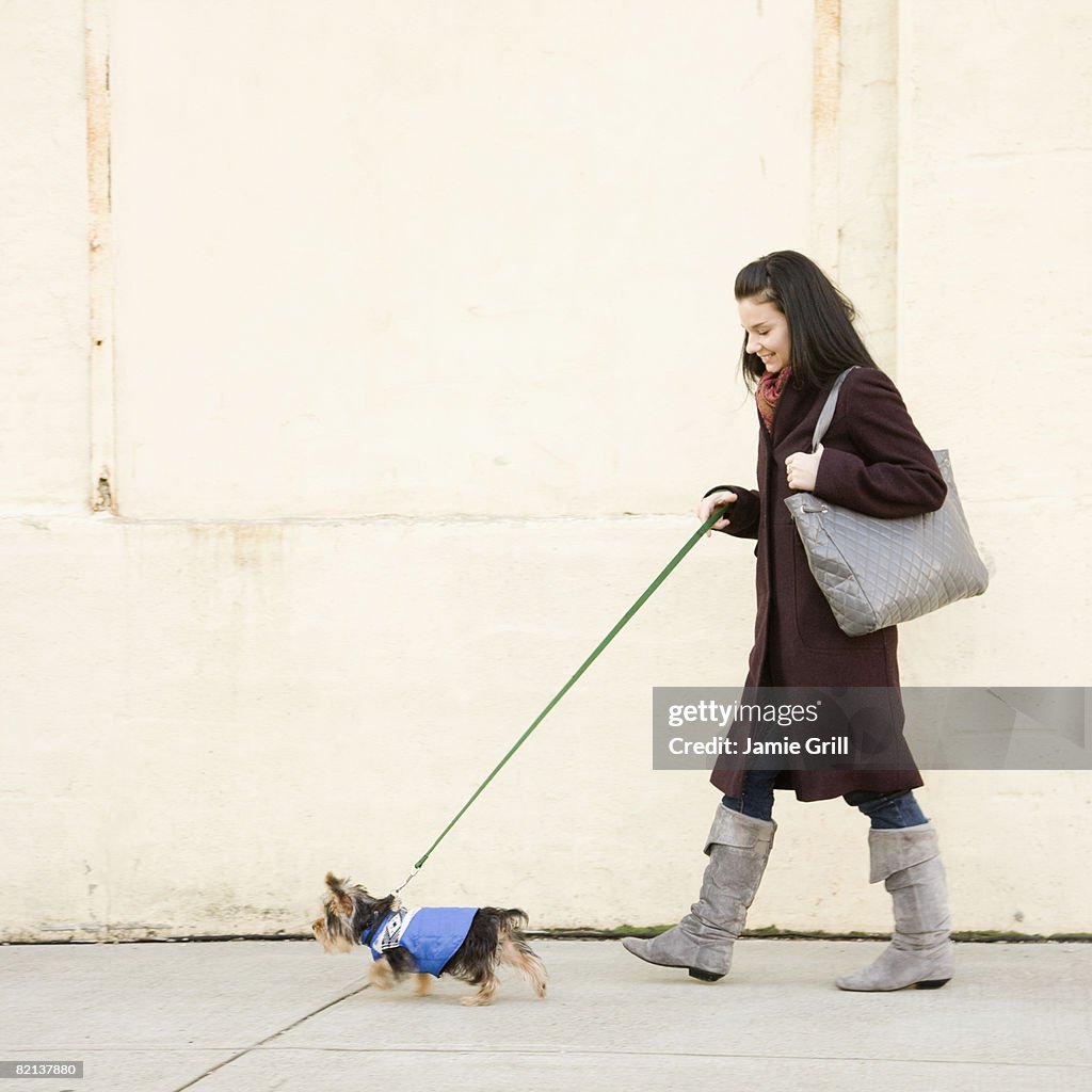 Woman walking dog on sidewalk