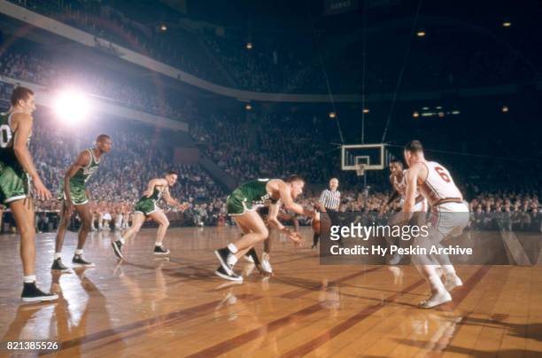 Jack Nichols of the Boston Celtics dribbles up the court as he is defended by Lou Costello and Earl Lloyd of the Syracuse Nationals during an NBA...