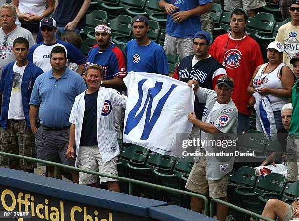 Fans of the Chicago Cubs hold up a win flag along the first baseline after the Cubs complete a four game sweep of the Milwaukee Brewers at Miller...