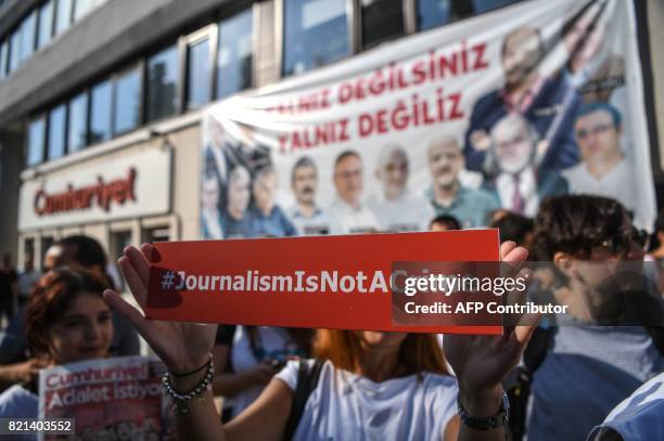 Journalist holds a banner on July 24, 2017 outside the headquarters of opposition daily newspaper Cumhuriyet in Istanbul. Seventeen directors and...