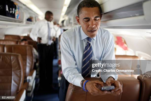 Presidential candidate Senator Barack Obama and Senator Hillary Rodham Clinton work their cellphones and chat together on his campaign plane at...