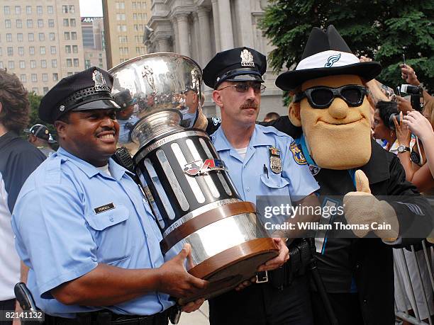 Philadelphia Police officers and the team mascot Soulman carry the Arena Bowl trophy during a championship parade at City Hall on July 27, 2008 in...