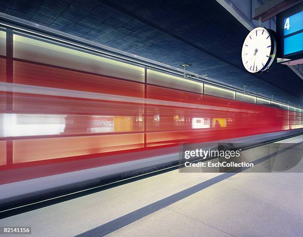 red train leaving train station (blurred because of long exposure time). - railroad station platform stock pictures, royalty-free photos & images