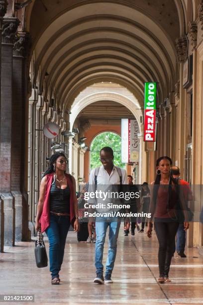 Abdoulaye walks into the porticos with two Malian migrants, who arrived in Italy just few months ago, to reach the public library on July 21, 2017 in...