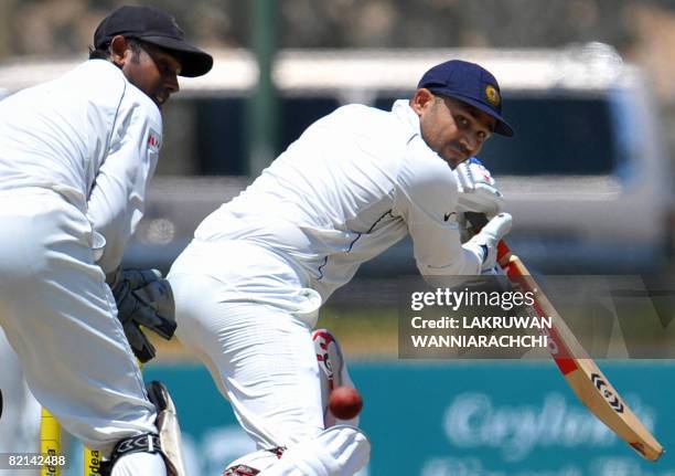 Indian cricketer Virender Sehwag is watched by Sri Lankan wicketkeeper Prasanna Jayawardene as he plays a stroke during the second day of the second...