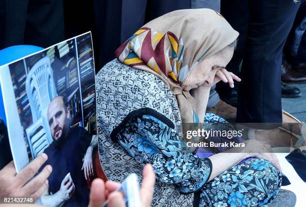 Woman sits out side the central Istanbul court as she is flanked by a photograph of Cumhuriyet newspaper's investigative journalist Ahmet Sik, during...