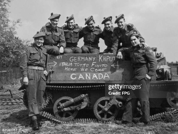 Canadian soldiers pose by their Bren carrier, shortly after 0800 hours when the World War II ceasefire came into effect, 5th May 1945. From left to...