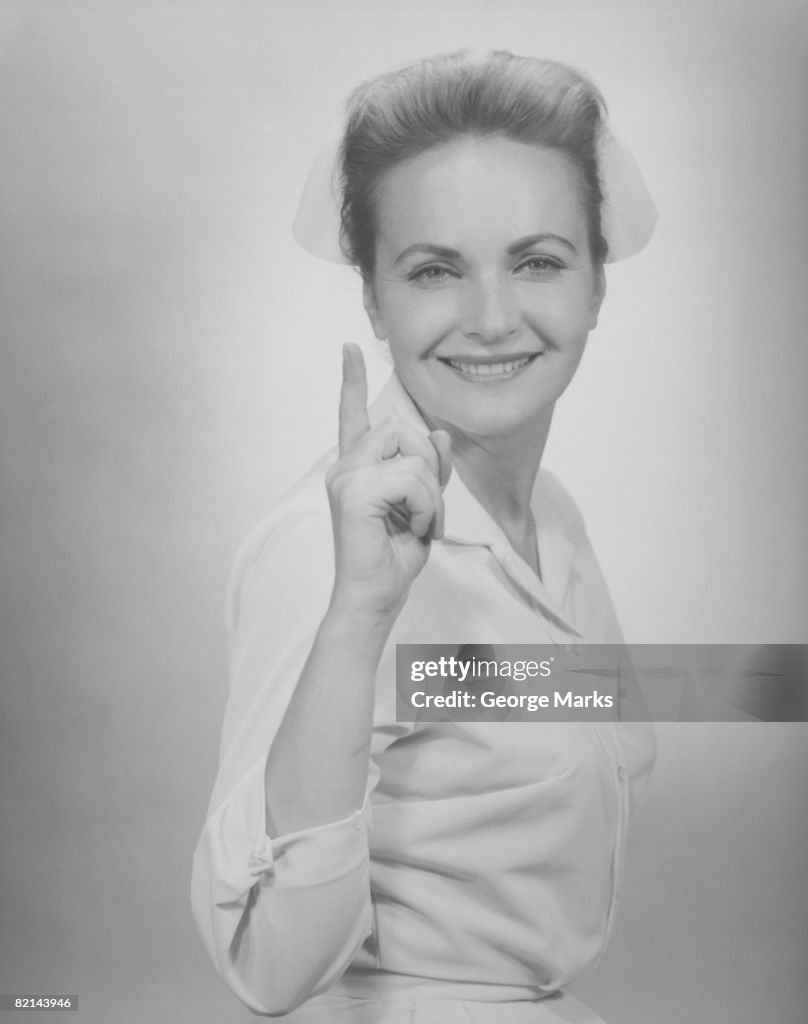 Nurse pointing in studio, (B&W), portrait