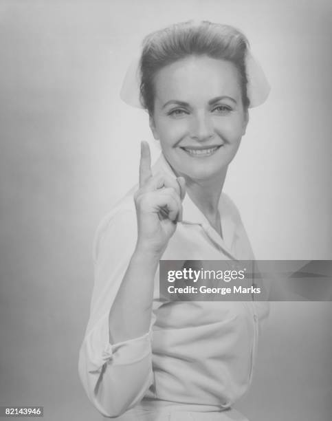 nurse pointing in studio, (b&w), portrait - nurse and portrait and white background and smiling and female and looking at camera stock pictures, royalty-free photos & images