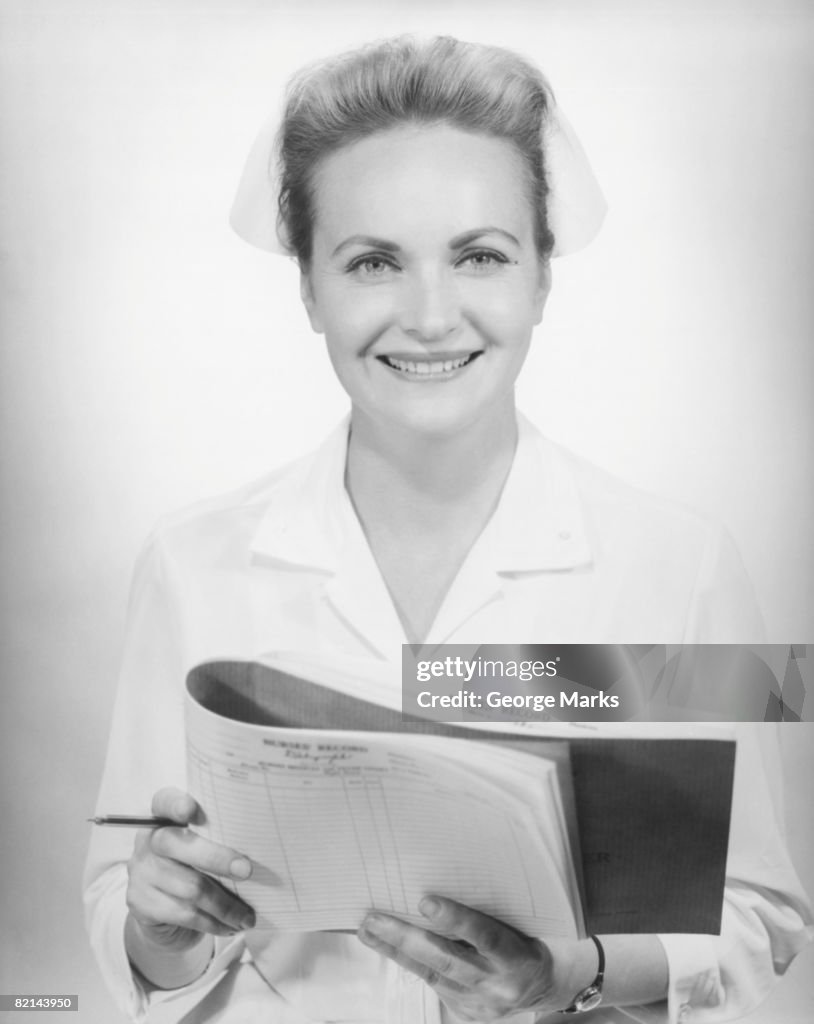 Nurse holding medical chart in studio, (B&W), portrait