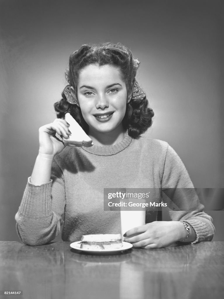 Woman having sandwich and milk, (B&W), portrait