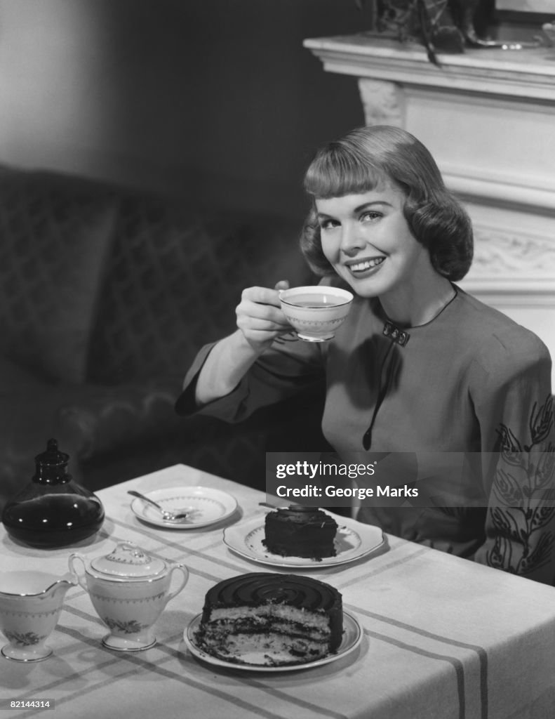 Woman having cake and coffee, (B&W)