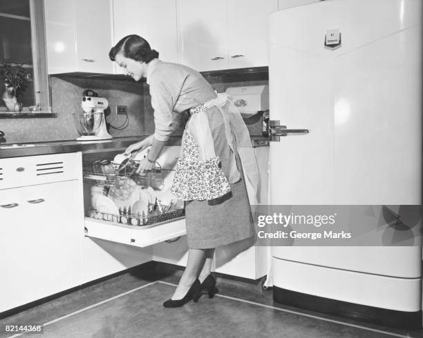 woman loading dishwasher, (b&w) - homemaker stock-fotos und bilder