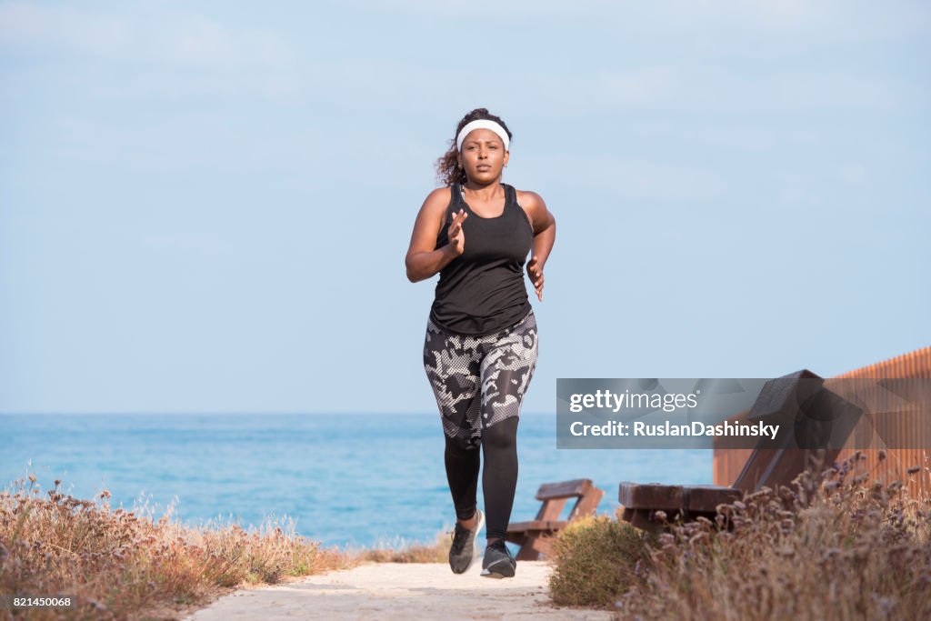 Fat woman on morning workout outdoors on the seacoast.