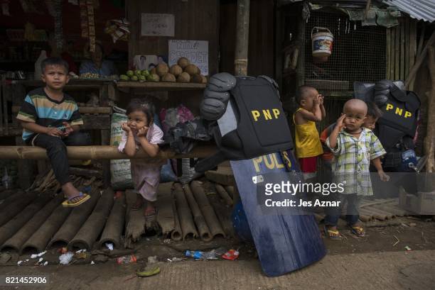 Police gear and shields are placed near playing displaced Marawi children on July 24, in Saguiaran, Lanao del Sur, southern Philippines. Evacuees...