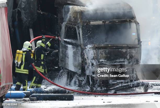 Firemen extiniguish a blaze in the driver's cab of a truck which caught fire following an accident on the A13 highway heading north on July 24, 2017...