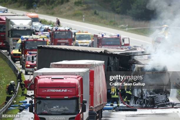 Firemen extiniguish a blaze in the driver's cab of a truck that caught fire following an accident on the A13 highway heading north on July 24, 2017...