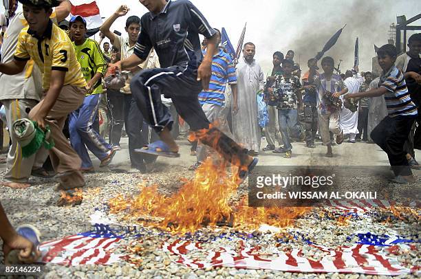 Iraqis burn US flags while rallying after Friday midday prayers in the populous Shiite stronghold district of Sadr City, on the outskirts of Baghdad...