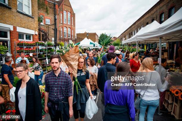 People shop at the Columbia Road Flower Market in east London on July 23, 2017. / AFP PHOTO / Tolga Akmen