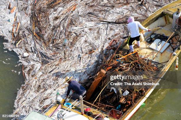 In this aerial image, fishermen collect driftwood which were washed by mudslide triggered by torrential rain starting July 5, at Ariake Sea on July...