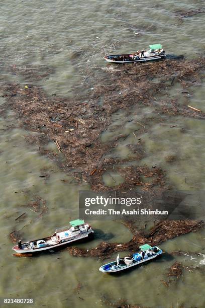 In this aerial image, fishermen collect driftwood which were washed by mudslide triggered by torrential rain starting July 5, at Ariake Sea on July...